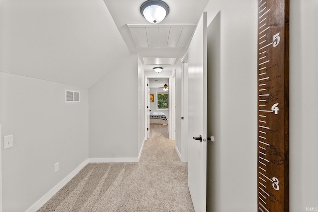 hallway with light carpet and vaulted ceiling