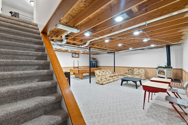 basement with carpet flooring, wooden walls, and a wood stove