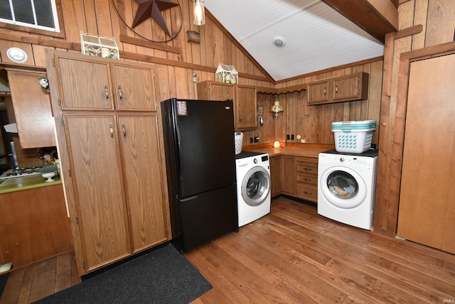 interior space with black fridge, wooden walls, vaulted ceiling, and washer / dryer