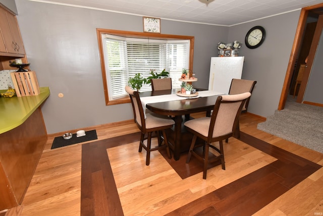 dining area featuring ornamental molding and light hardwood / wood-style flooring