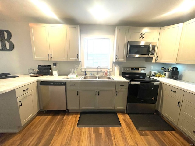 kitchen with light hardwood / wood-style floors, appliances with stainless steel finishes, sink, and white cabinets