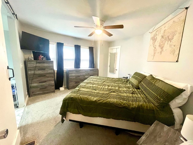 bedroom with ceiling fan, light colored carpet, and a closet