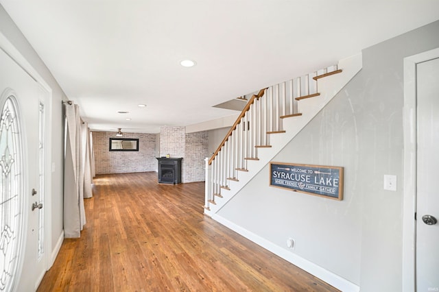 entrance foyer featuring hardwood / wood-style flooring, a wood stove, and brick wall