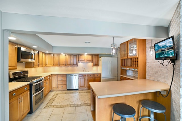 kitchen with light tile patterned floors, a kitchen bar, kitchen peninsula, stainless steel appliances, and brick wall