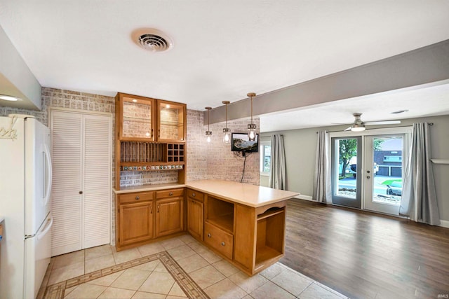 kitchen with decorative light fixtures, ceiling fan, white fridge, kitchen peninsula, and light tile patterned floors