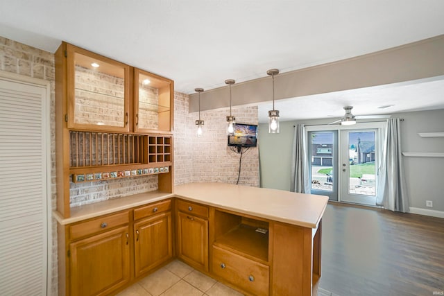 kitchen featuring decorative light fixtures, kitchen peninsula, brick wall, and ceiling fan