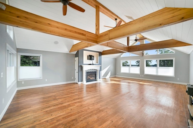 unfurnished living room featuring hardwood / wood-style flooring, beam ceiling, plenty of natural light, and high vaulted ceiling