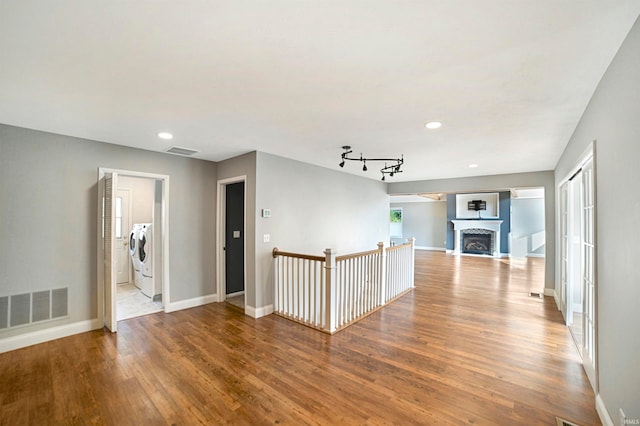 corridor featuring hardwood / wood-style flooring, separate washer and dryer, and track lighting