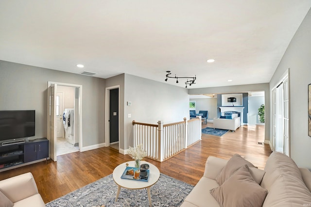 living room featuring washer / clothes dryer, rail lighting, and hardwood / wood-style flooring