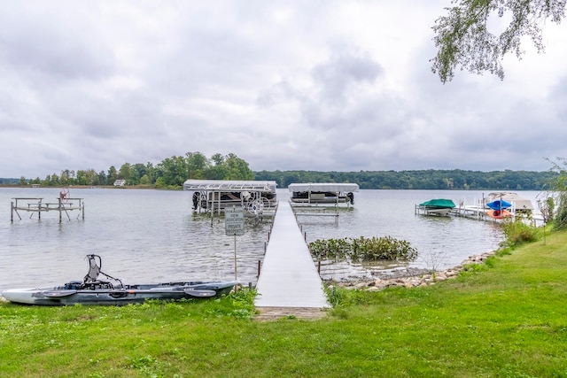 view of dock with a lawn and a water view