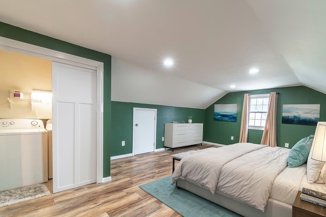 bedroom with light wood-type flooring, lofted ceiling, and washer and dryer