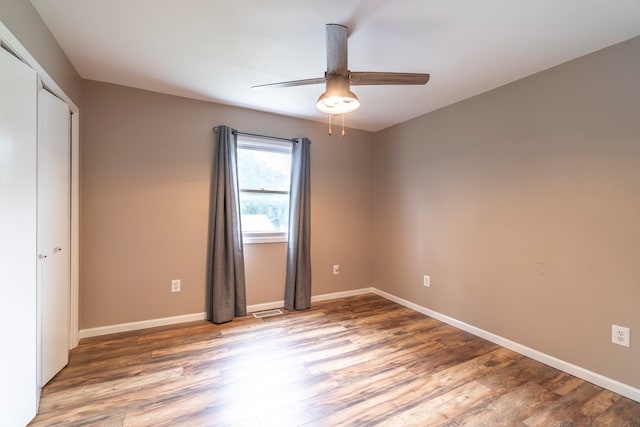 unfurnished bedroom with ceiling fan, hardwood / wood-style flooring, and a closet