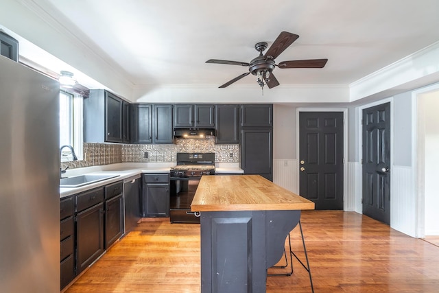 kitchen featuring light wood-type flooring, sink, butcher block counters, a kitchen bar, and stainless steel appliances