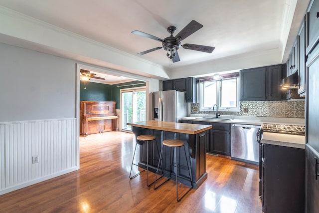 kitchen featuring a breakfast bar, a center island, appliances with stainless steel finishes, and hardwood / wood-style flooring