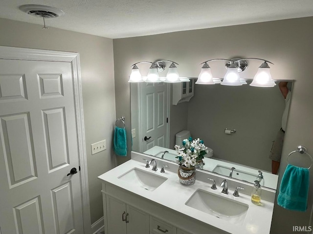 bathroom with vanity, toilet, and a textured ceiling