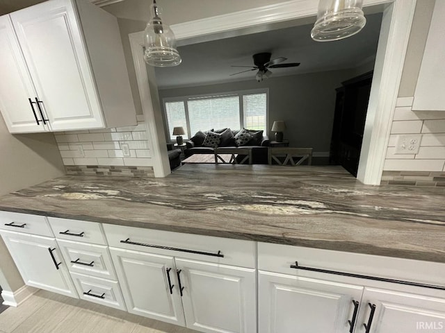 kitchen featuring tasteful backsplash, open floor plan, white cabinetry, ceiling fan, and decorative light fixtures