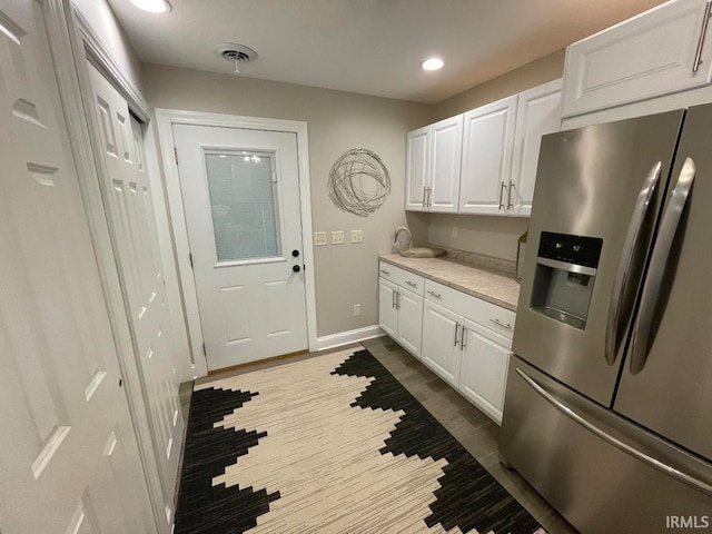 kitchen with stainless steel fridge, hardwood / wood-style flooring, and white cabinets