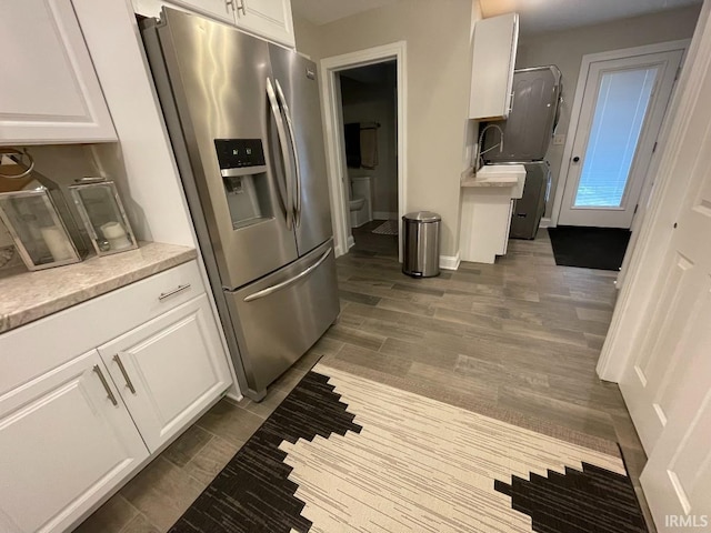 kitchen with dark wood finished floors, stainless steel fridge with ice dispenser, white cabinetry, and light countertops