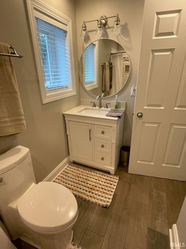 bathroom with wood-type flooring, vanity, and toilet