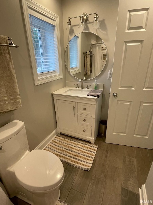 bathroom featuring baseboards, wood finished floors, vanity, and toilet