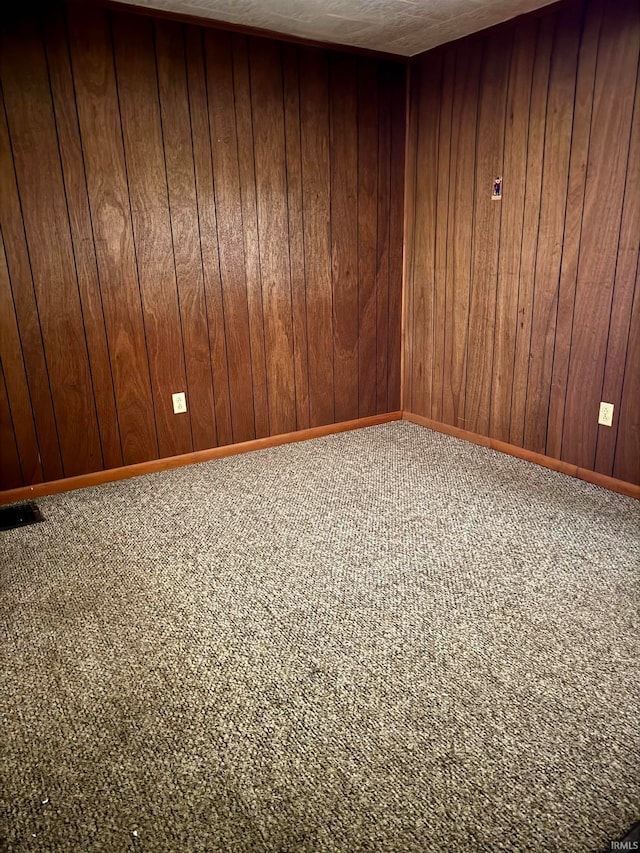 unfurnished room with wooden walls and carpet