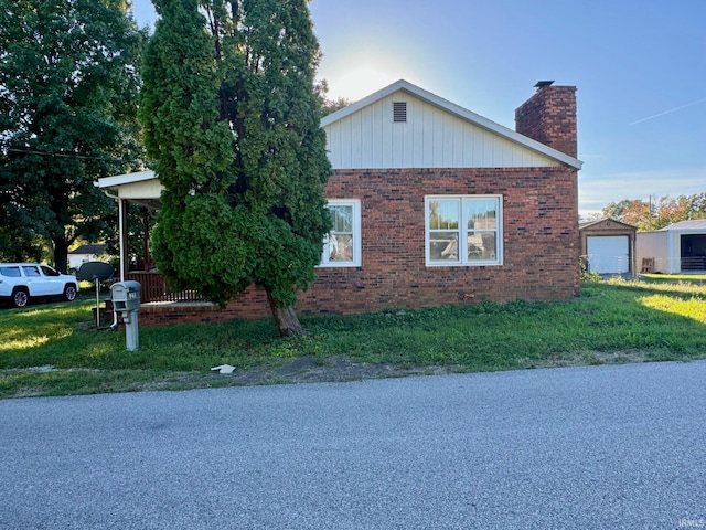 view of side of home with a garage, an outdoor structure, and a lawn