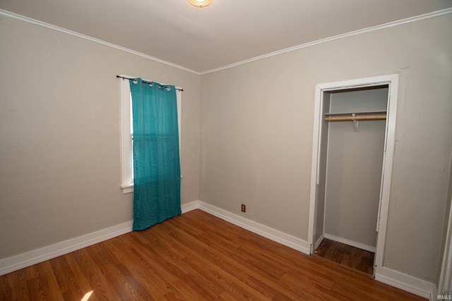 unfurnished bedroom with wood-type flooring, a closet, and ornamental molding