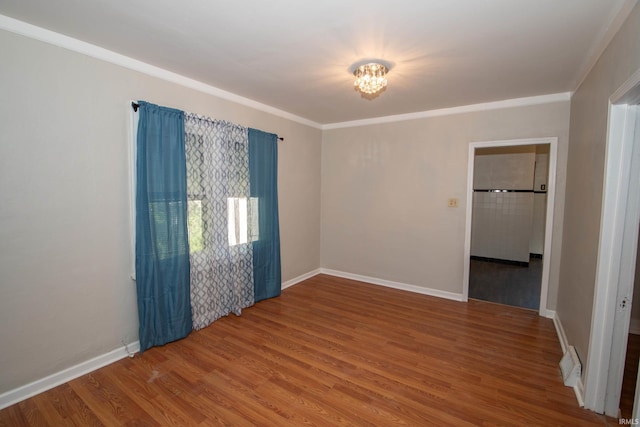 empty room with hardwood / wood-style flooring and ornamental molding