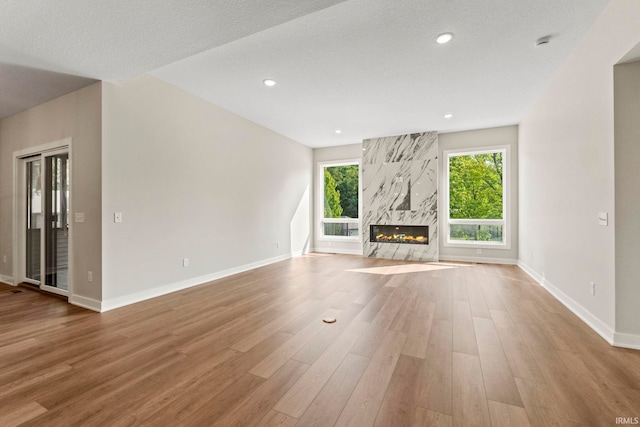 unfurnished living room featuring a textured ceiling, light wood-type flooring, and a premium fireplace