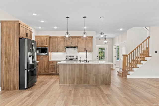 kitchen with decorative light fixtures, a kitchen island with sink, and appliances with stainless steel finishes