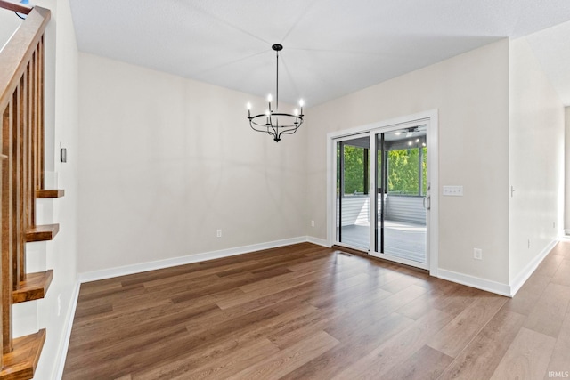 unfurnished dining area with hardwood / wood-style floors and a notable chandelier