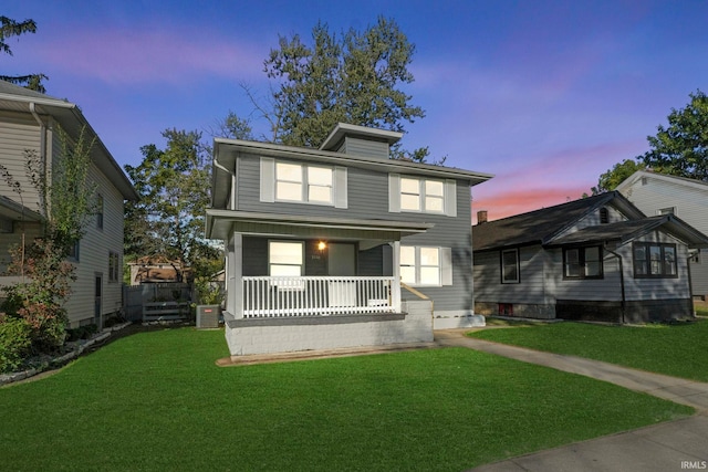 view of front facade with a yard, central air condition unit, and covered porch