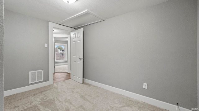 empty room with light carpet and a textured ceiling