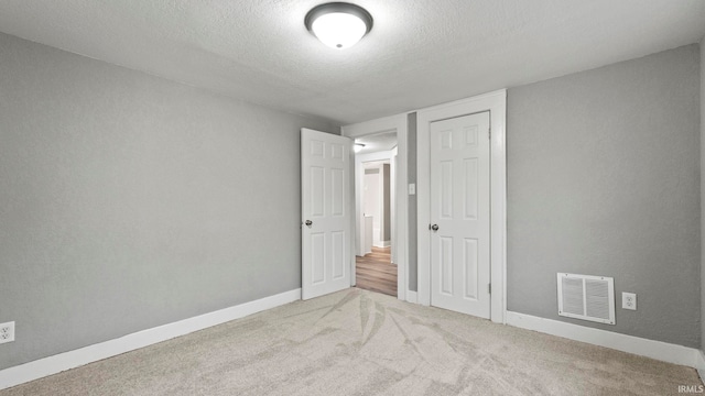 unfurnished bedroom with a closet, a textured ceiling, and carpet floors