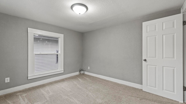 spare room featuring a textured ceiling and light colored carpet