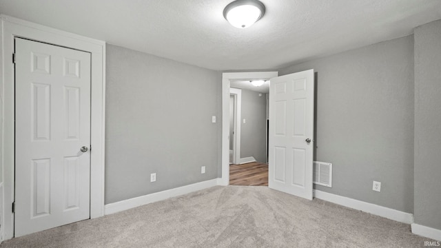 unfurnished bedroom with a textured ceiling and carpet