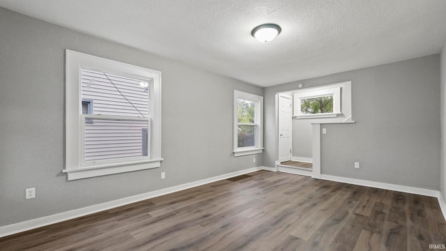 spare room featuring a textured ceiling and dark hardwood / wood-style flooring