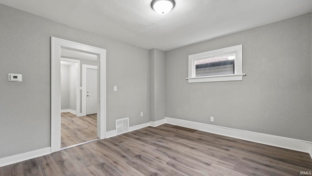 empty room with a textured ceiling and hardwood / wood-style floors