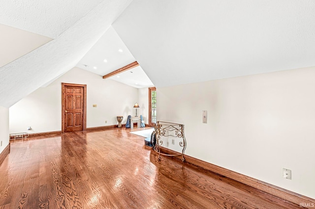 additional living space featuring wood-type flooring, a textured ceiling, and lofted ceiling