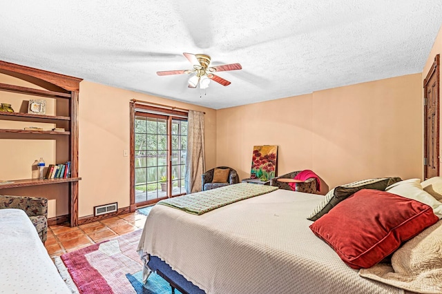 bedroom featuring ceiling fan, light tile patterned floors, and a textured ceiling