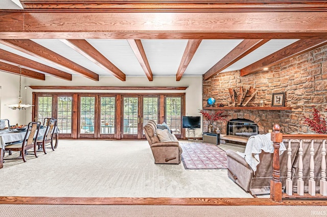 carpeted living room featuring beamed ceiling, a healthy amount of sunlight, and a stone fireplace