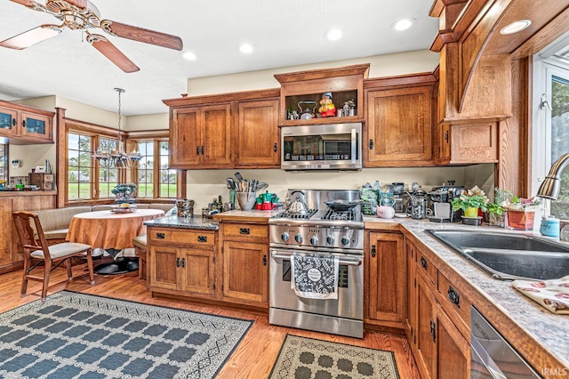 kitchen featuring sink, light hardwood / wood-style flooring, stainless steel appliances, decorative light fixtures, and ceiling fan