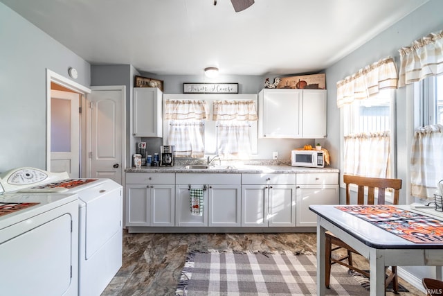 kitchen featuring white cabinetry, washer and dryer, and sink