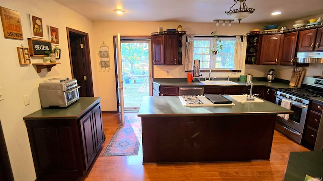 kitchen with a center island with sink, stainless steel appliances, light hardwood / wood-style floors, and a wealth of natural light