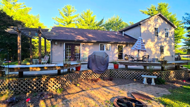 back of house with a deck, a pergola, a patio area, and an outdoor fire pit