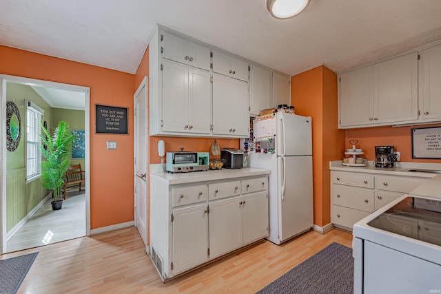 kitchen featuring white refrigerator, white cabinetry, and range with electric cooktop