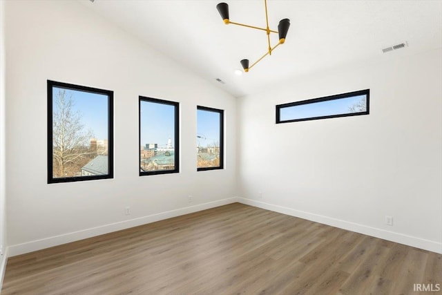 unfurnished room featuring visible vents, baseboards, and wood finished floors