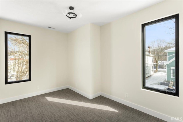 carpeted spare room with visible vents and baseboards