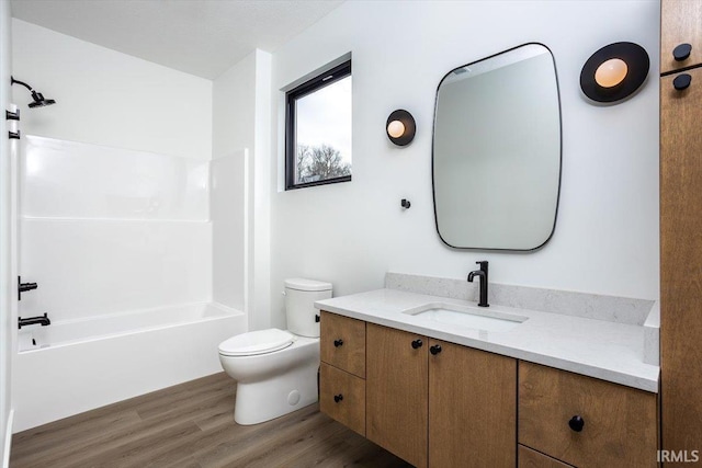 full bath with bathtub / shower combination, vanity, toilet, and wood finished floors