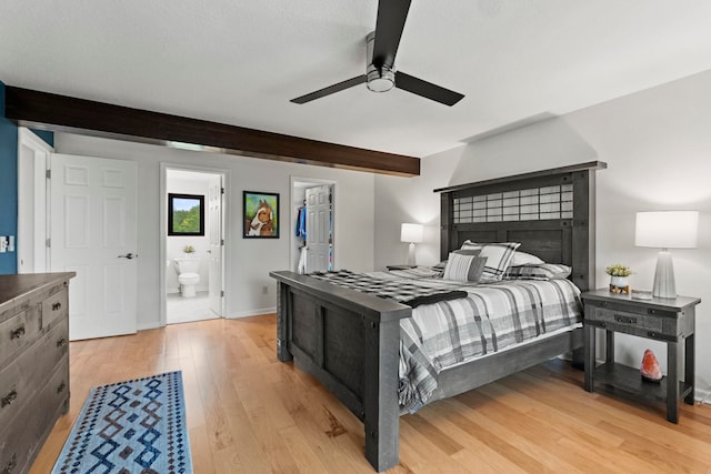 bedroom featuring light hardwood / wood-style flooring, ensuite bath, ceiling fan, and beamed ceiling